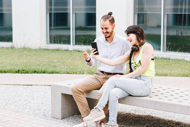 istock Cute woman showing an handsome man her cell phone screen. 1271989471