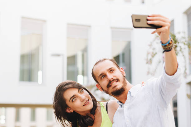 istock Young couple making a selfie seated on a bench at campus. 1271989477