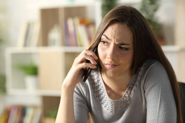 istock Suspicious woman calling on phone sitting at home 1271990336