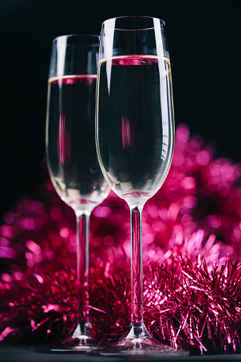 Two champagne glasses with christmas and new years decoration bokeh on dark background.