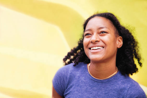 feliz jovem retrato feminino negro sorrindo totalmente em frente a uma parede amarela - setembro amarelo - fotografias e filmes do acervo