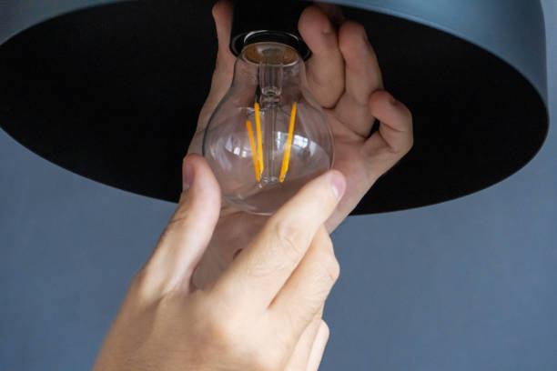istock Close-up. A hand changes a light bulb in a stylish loft lamp. Spiral filament lamp. Modern interior decor. 1271994748