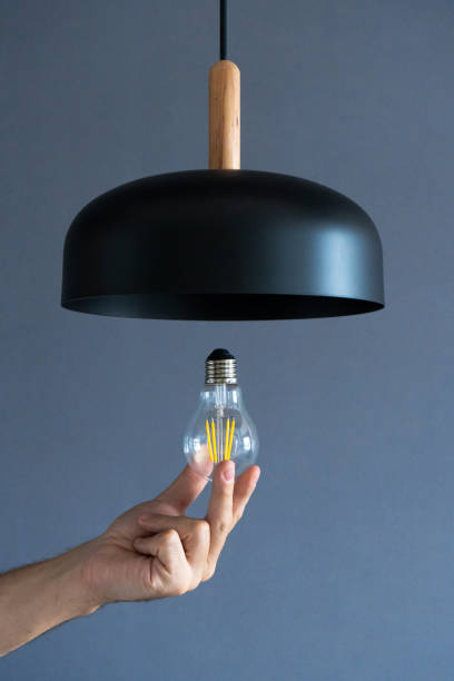 istock Close-up. A hand changes a light bulb in a stylish loft lamp. Spiral filament lamp. Modern interior decor. 1271995008