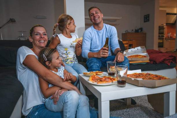 caucasian family sitting on a sofa eating pizza and watching tv - 5461 imagens e fotografias de stock