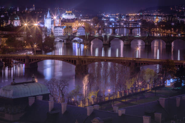 prague panorama with bridges, boat motion and vltava river at night – czech republic - prague mirrored pattern bridge architecture imagens e fotografias de stock