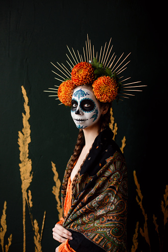 Portrait of young woman wearing makeup for Halloween inspired by the mexican celebration.