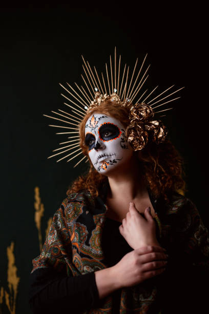 Attractive young woman with sugar skull makeup on dark background
