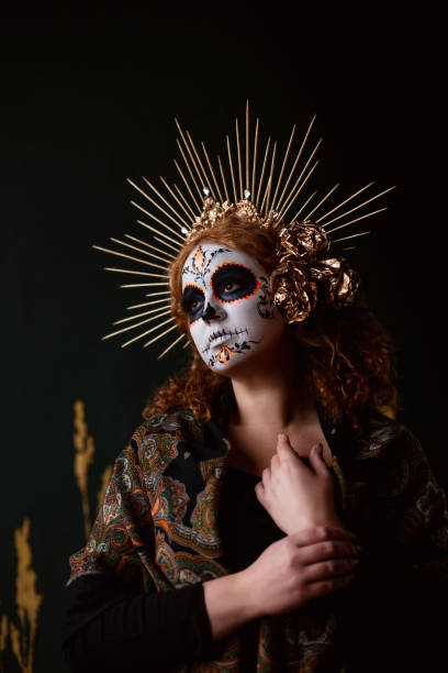 Attractive young woman with sugar skull makeup on dark background Portrait of woman with traditional make up for Dia de los Muertos golden roses stock pictures, royalty-free photos & images