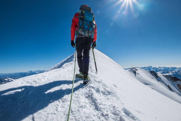 istock Last steps before Mont Blanc (Monte Bianco) summit 4,808 m of man with climbing axe dressed mountaineering clothes, boots with crampons walking by snowy slopes with blue sky background with bright sun 1272011436