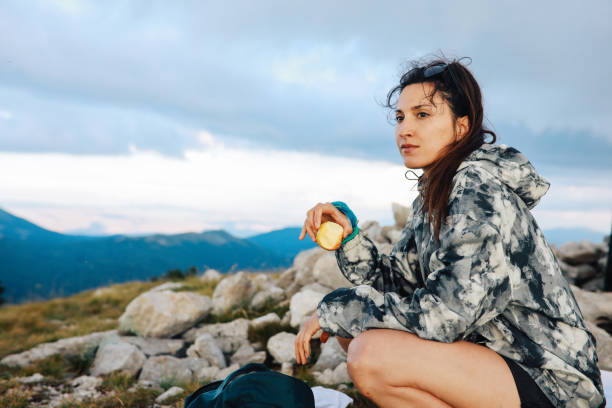 Woman hiking in the great outdoors, in the Dynamic Alps in Southern Europe. She is taking a short break, eating an apple for some extra energy.