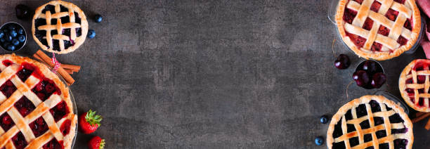 istock Homemade fruit pies. Overhead view double border over a dark stone background. 1272018166