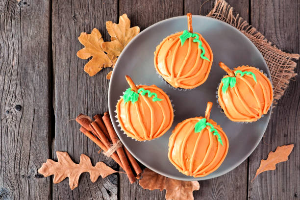 istock Plate of autumn pumpkin cupcakes on a rustic wood background 1272018967