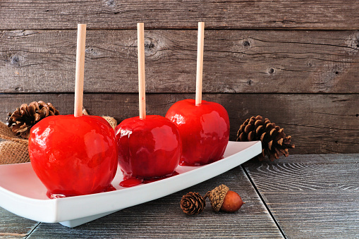 Traditional red candied apples. Side view against a rustic wood background. Halloween or fall treat.