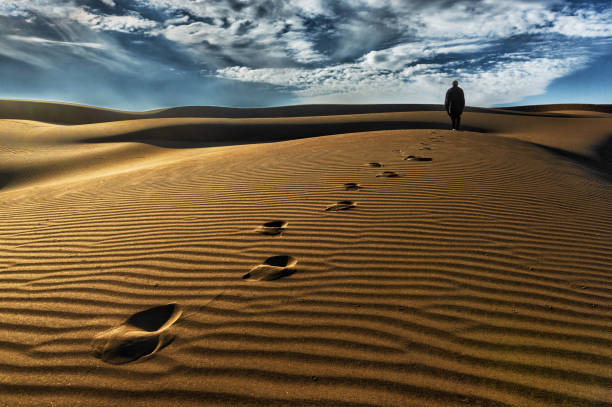 istock A man walks along a dune, leaving traces 1272030099
