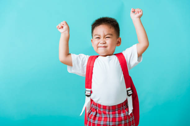 istock child boy in uniform smile raise hands up glad when go back to school 1272031775
