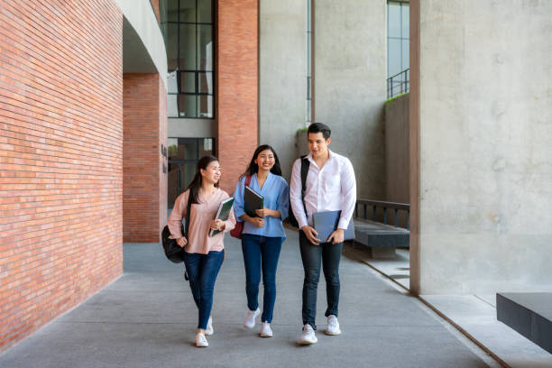 istock Asian three students are walking and talking together in university hall during break in University. 1272043850