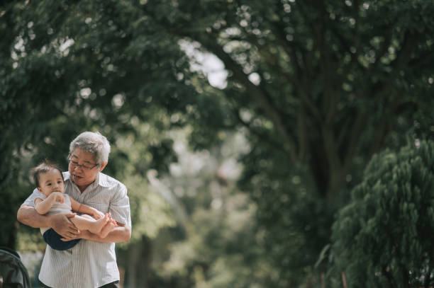 azjatycki chiński dziadek niosący wnuka chłopca w publicznym parku rano - grandfather baby grandson grandparent zdjęcia i obrazy z banku zdjęć