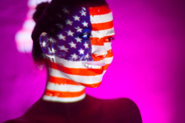 istock Young woman smiling with USA flag on her face 1272047155