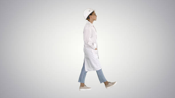 istock Walking woman engineer with hands in pockets on gradient background 1272047339