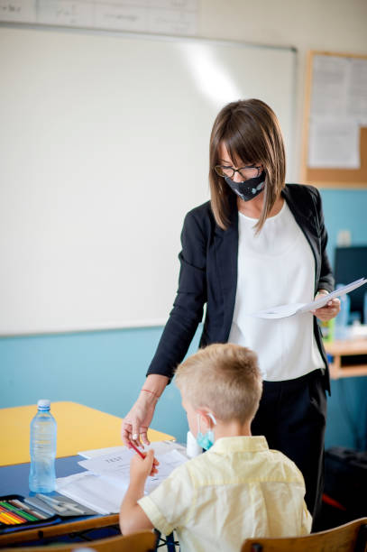 istock Teacher and children with face mask back at school 1272049487