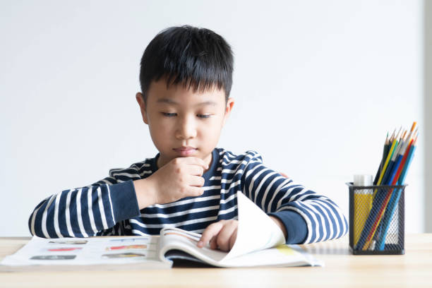 istock Asian boy who is studying in elementary school reading and doing homework by himself at home. 1272050445