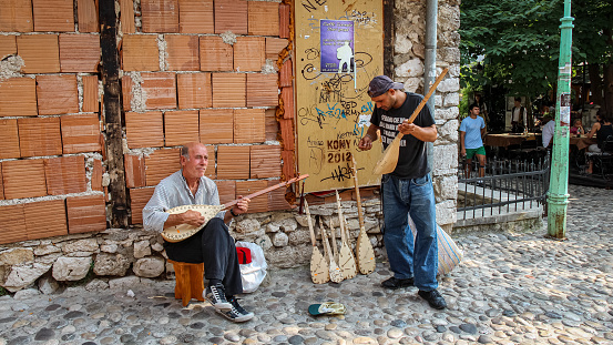 Mostar, Bosnia and Herzegovina - July 4th 2018: Two buskers on the street in Mostar playing the Sargija, a traditional balkan musical instrument, Bosnia and Herzegovina