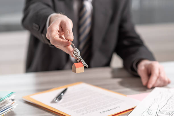 istock Estate agent offering house keys 1272065091