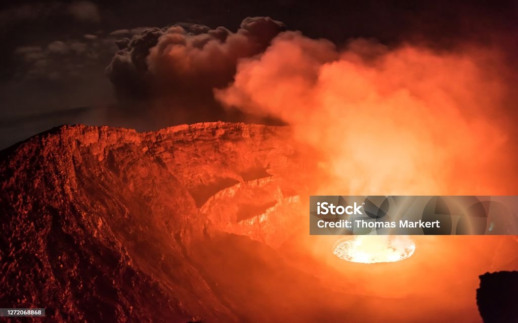 Glowing clouds of smoke emitted from lava lake inside active Nyiragongo volcano lit by moonlight Wide angle shot of lava lake and smoke in Nyiragongo volcano Volcano Stock Photo