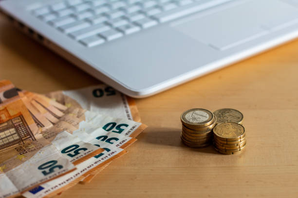 istock Coins and banknotes with a white computer on a wooden table in the office. 1272069203