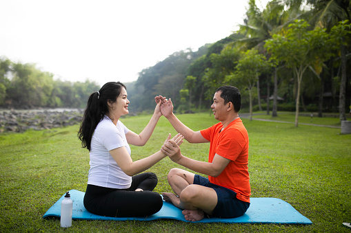 Shot of asian couple calmly engaging in a yoga pose with their legs crossed