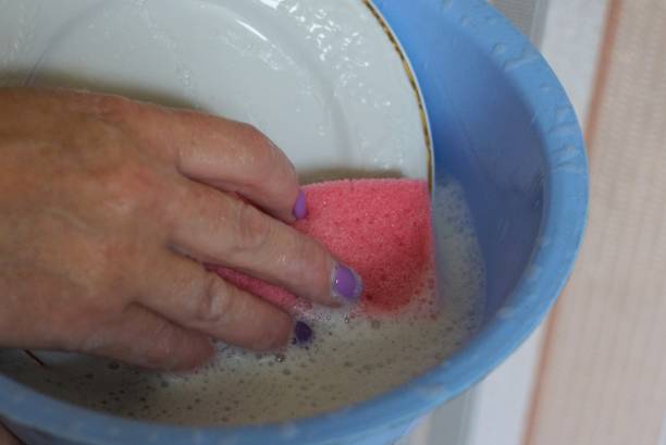 istock woman's hand with a red washcloth washes a white plate 1272072575