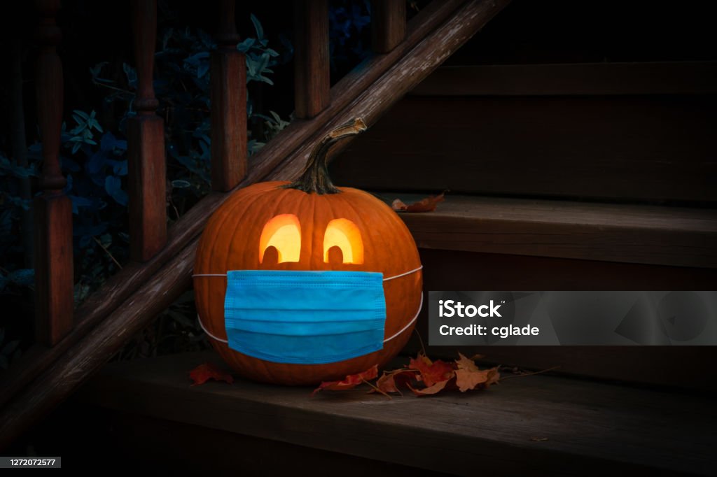 Beleuchtete Halloween Kürbis Jack o Laterne tragen Covid PPE Maske auf Stufen - Lizenzfrei Halloween Stock-Foto
