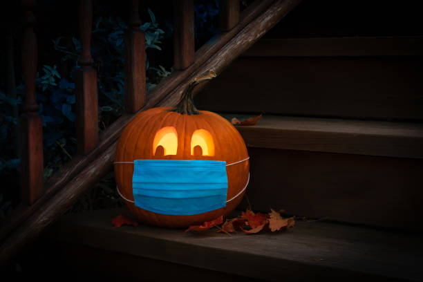 Lighted Halloween Pumpkin Jack o Lantern Wearing Covid PPE Mask On Steps Lighted Halloween Pumpkin Jack o Lantern Wearing Covid PPE Mask On Steps trick or treat photos stock pictures, royalty-free photos & images