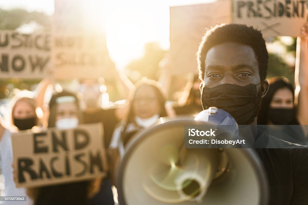 People from different culture and races protest on the street for equal rights People from different culture and races protest on the street for equal rights. Focus on black man eyes Racism Stock Photo