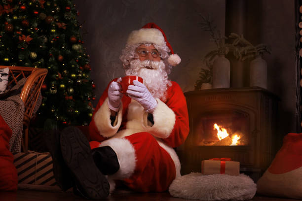 istock Santa Claus having a rest in a comfortable chair near the fireplace at home. 1272073708