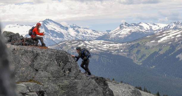 female mountaineer belays friend ascending mountain ridge - 24256 imagens e fotografias de stock