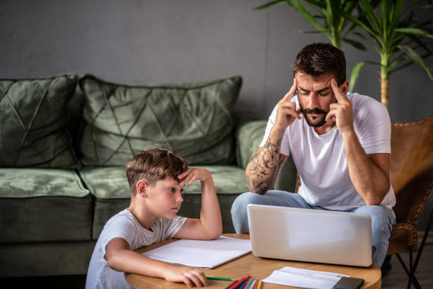 istock Father working on laptop and concentrating on work while his son sits next to him and thinks about what to draw 1272081887