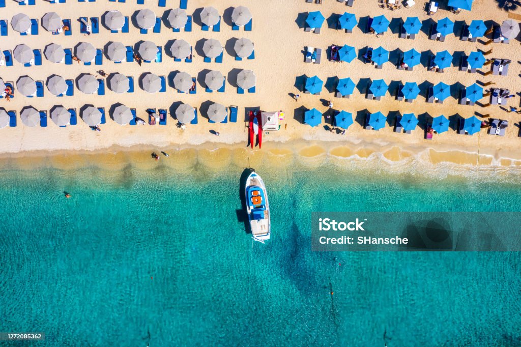 Aerial top down view to the umbrellas at the beach of Ornos, Mykonos, Greece Aerial top down view to the umbrellas and the turquoise sea at the popular beach of Ornos, Mykonos island, Greece Mykonos Stock Photo