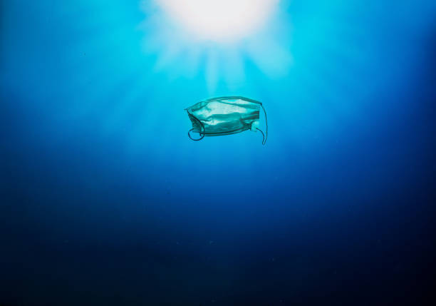 istock Concept of pollution with a facemask floating under water in the blue sea 1272085372
