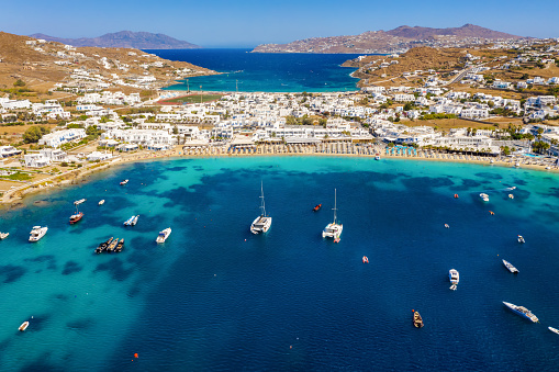 Aerial view to the popuar bay of Ornos on the island of Mykonos, Greece, with many yachts moored in front of the beautiful beach
