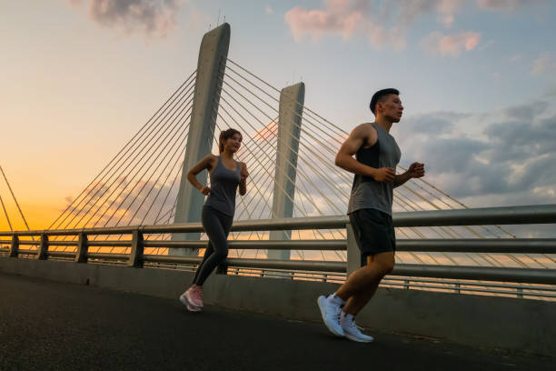 jovem casal correndo na ponte pela manhã - couple stretching running jogging - fotografias e filmes do acervo