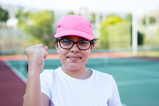 a girl who wears pink hat is doing victory sign with her hand on the hardcourt