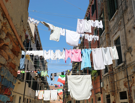 many clean clothes hanging out to dry in the sun and an Italian flag in the historic city center