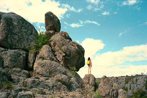 Young Caucasian woman near rock formation in summer