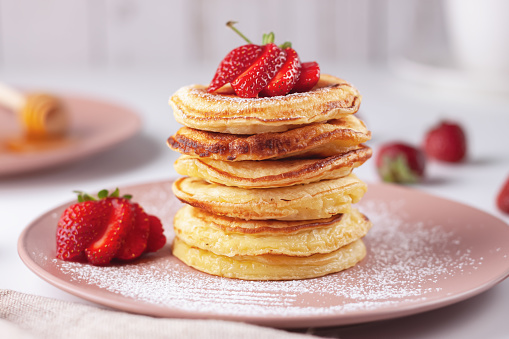 Freshly baked pancakes with strawberries on a natural wood background