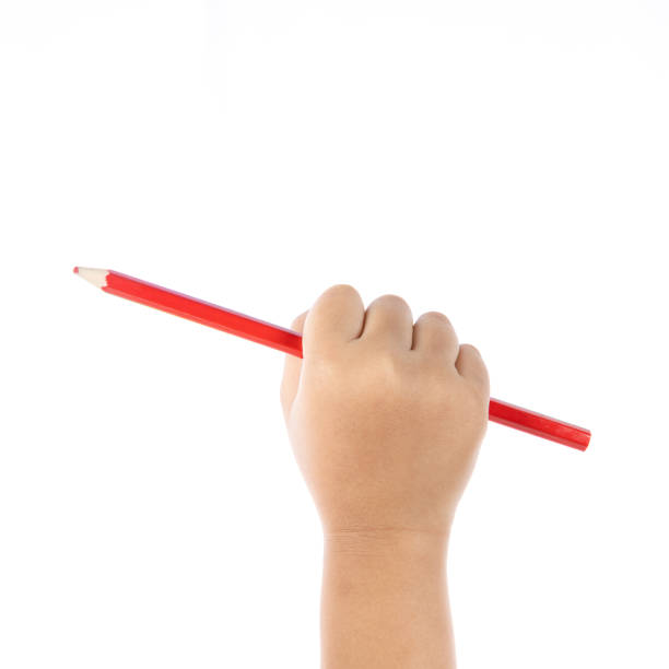 Child hand draws a crooked heart with a red pencil on white paper