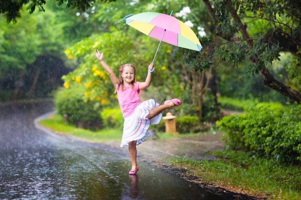 istock Kid with umbrella playing in summer rain. 1272095830