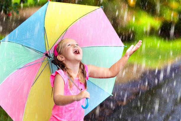 istock Kid with umbrella playing in summer rain. 1272096295
