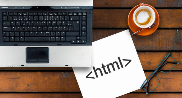 istock Paper width html tag and laptop, glasses and coffee on wooden table 1272097006