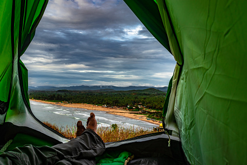 man at camping tent inside view of amazing landscape seashore image is taken at gokarna karnataka india. it is showing the human love towards the nature.